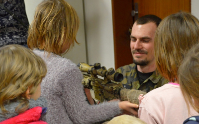 Policista ukazuje dětem jednu ze zbraní.