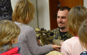 Policista ukazuje dětem jednu ze zbraní.