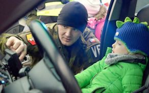 Chlapec si prohlíží vnitřek služebního auta vojenských policistů.